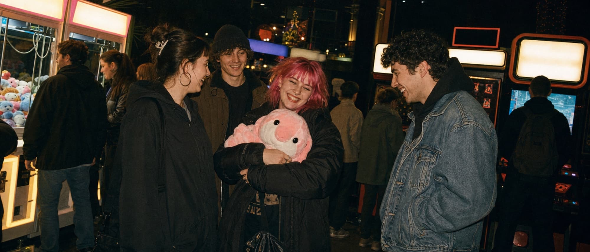 Groupe d’amis riant devant les machines à pinces d’une salle d’arcade la nuit